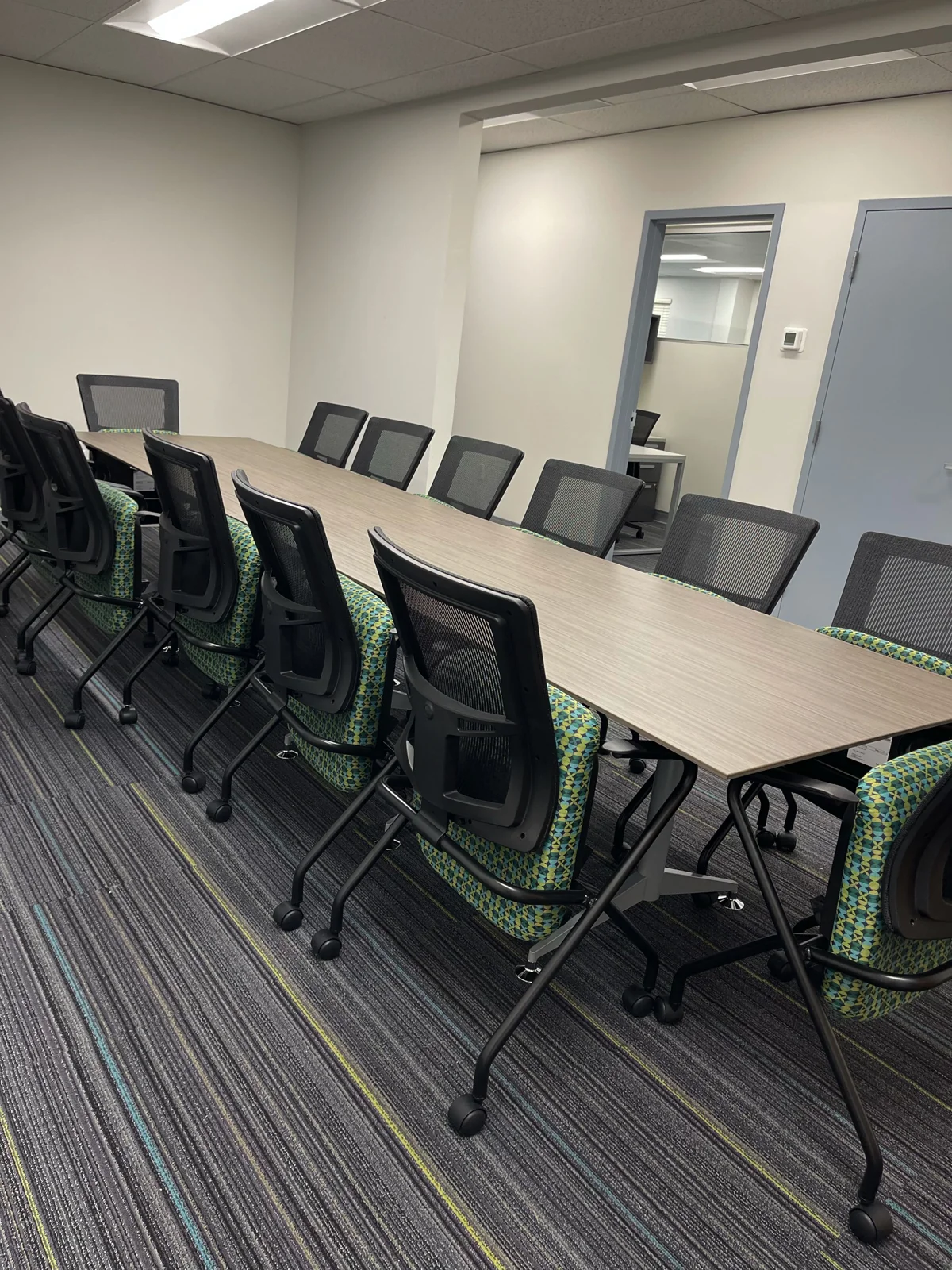 Long conference table with black rolling chairs in a meeting room